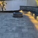 outdoor kitchen design with beautiful landscape lighting and stone paving.