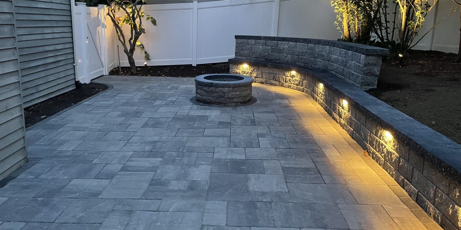 - Leahy Landscaping outdoor kitchen design with beautiful landscape lighting and stone paving.