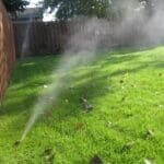 irrigation installation with a brown fence and green lawn