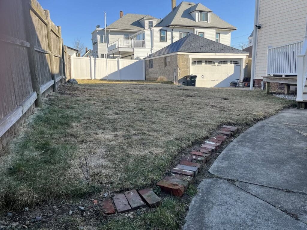 leahy-landscaping-north-shore - Leahy Landscaping Backyard with patchy grass and uneven lawn before landscaping upgrade on the North Shore of Massachusetts