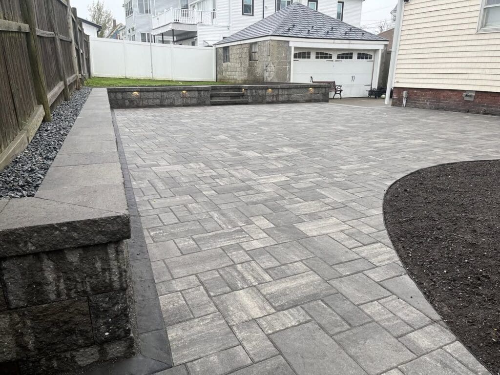 leahy-landscaping-north-shore-ma - Leahy Landscaping Fully landscaped backyard with new paver patio, retaining wall, and clean edging after professional landscaping in North Shore MA